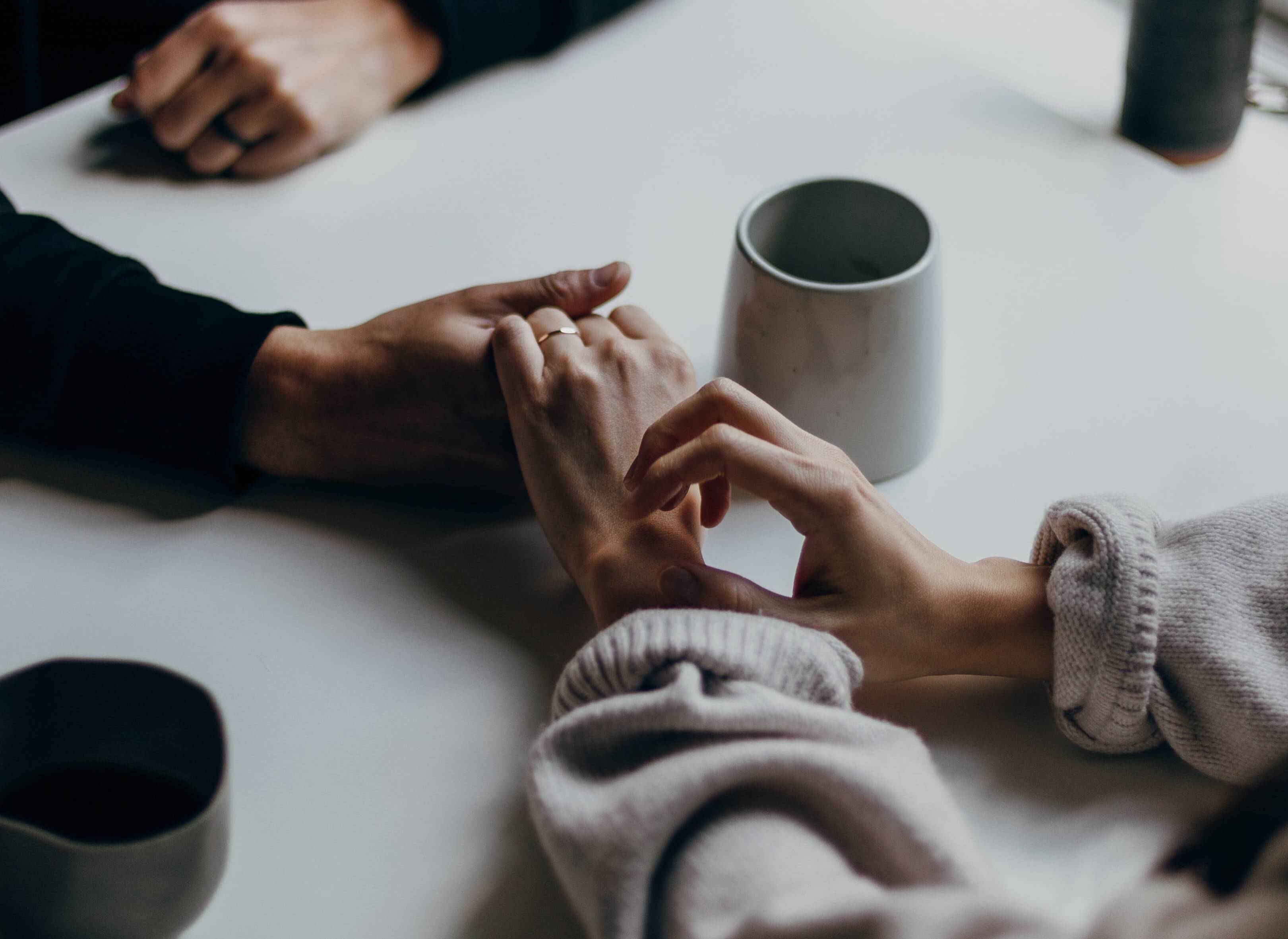 two people holding hands over the table